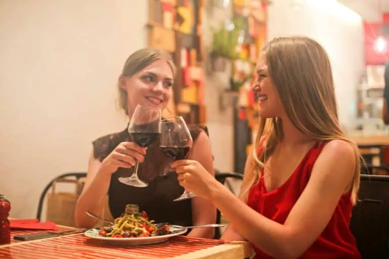 Two women sharing a joyful moment over dinner and wine at a cozy restaurant.